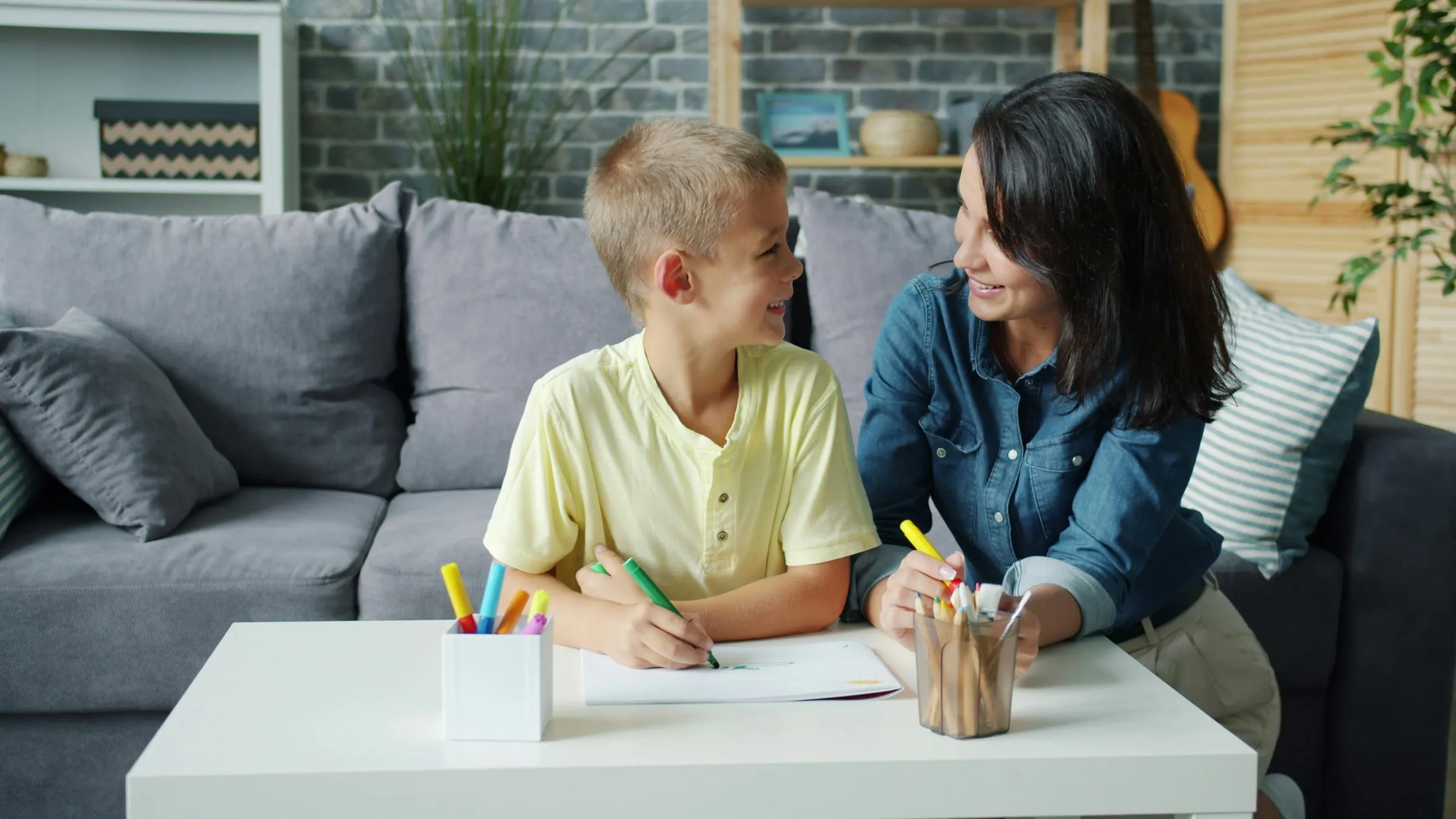 A boy drawing with his therapist at a low table