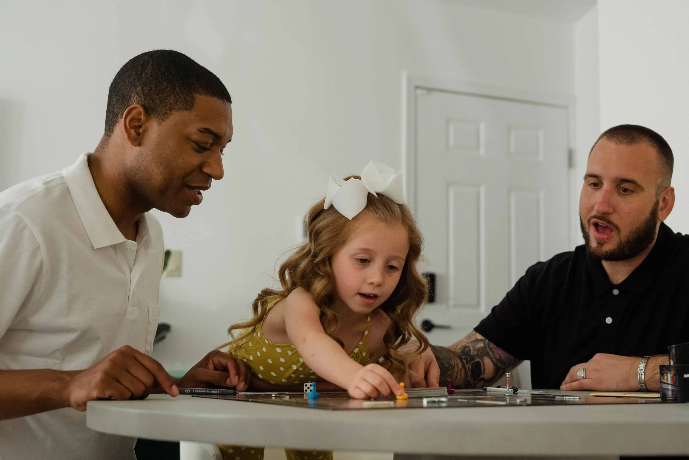 Two parents and their young daughter playing a board game together
