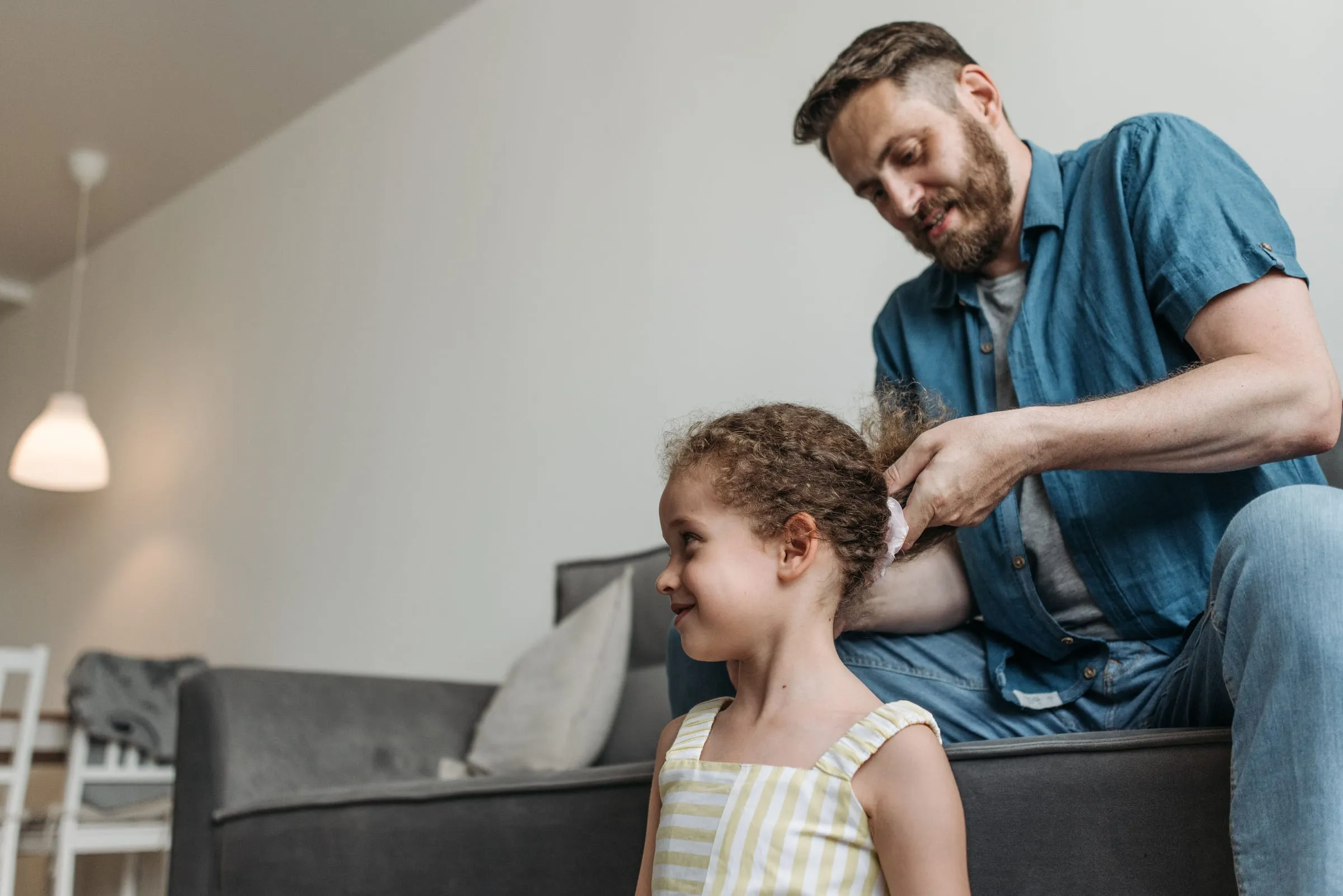 A father doing his young daughter's hair at home