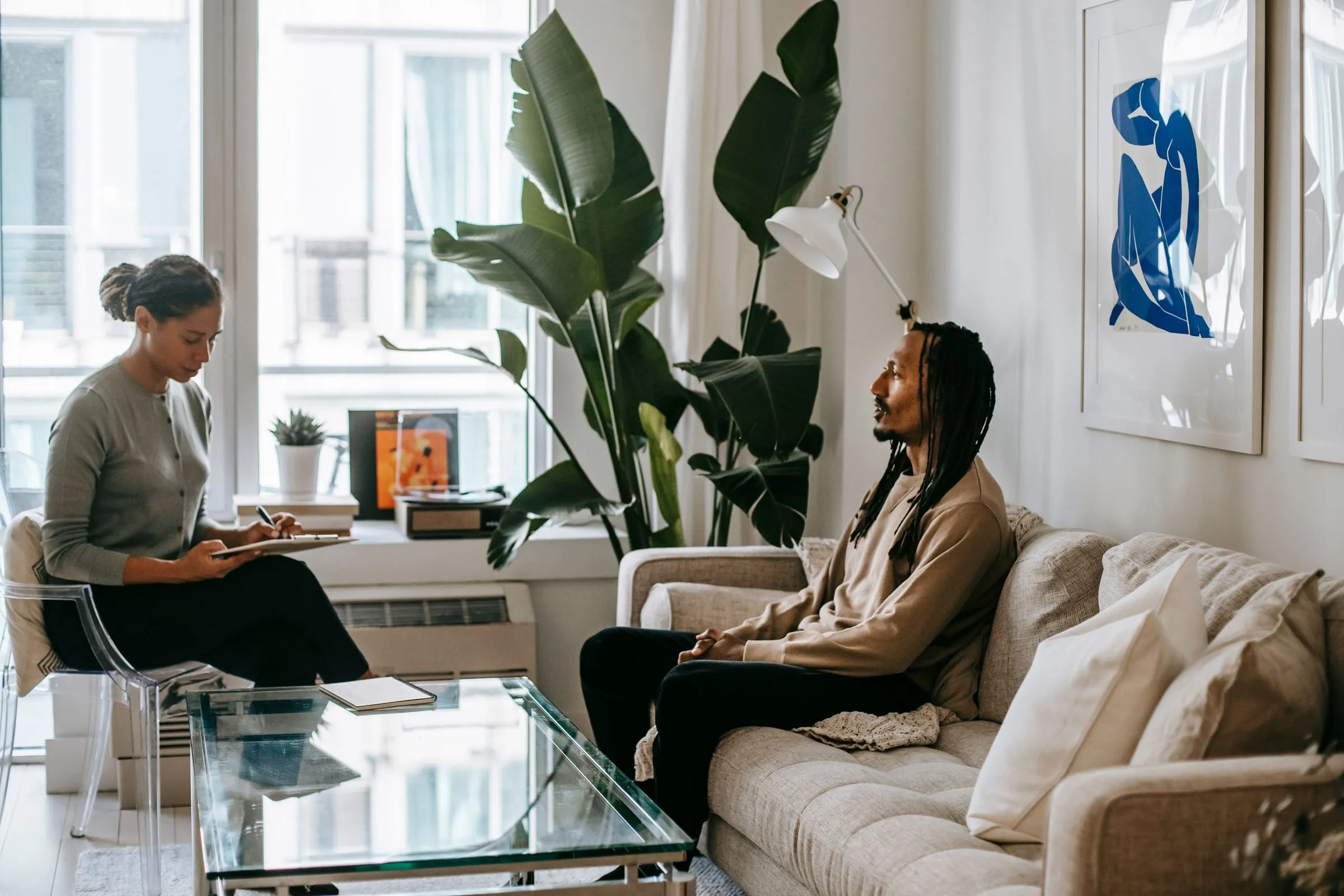 A therapist listening to a client in a bright office filled with plants