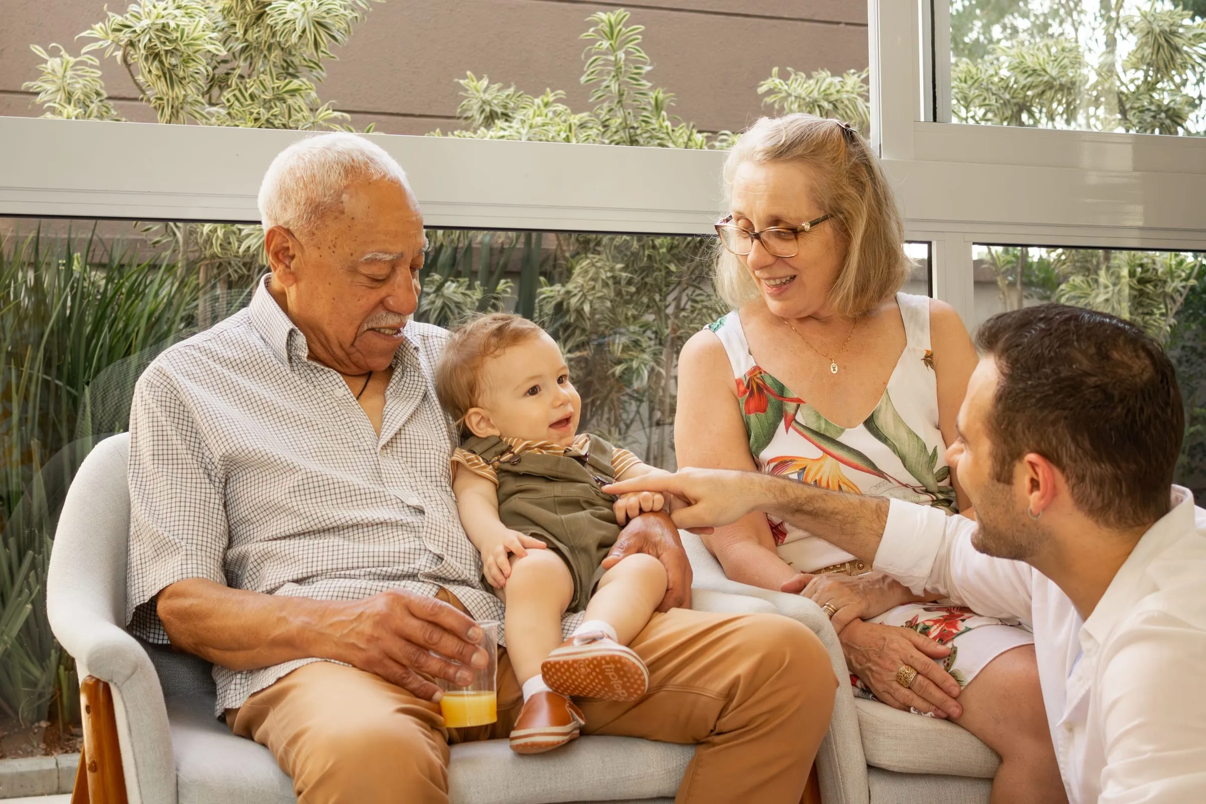 Grandparents, a father, and a baby laughing together at home