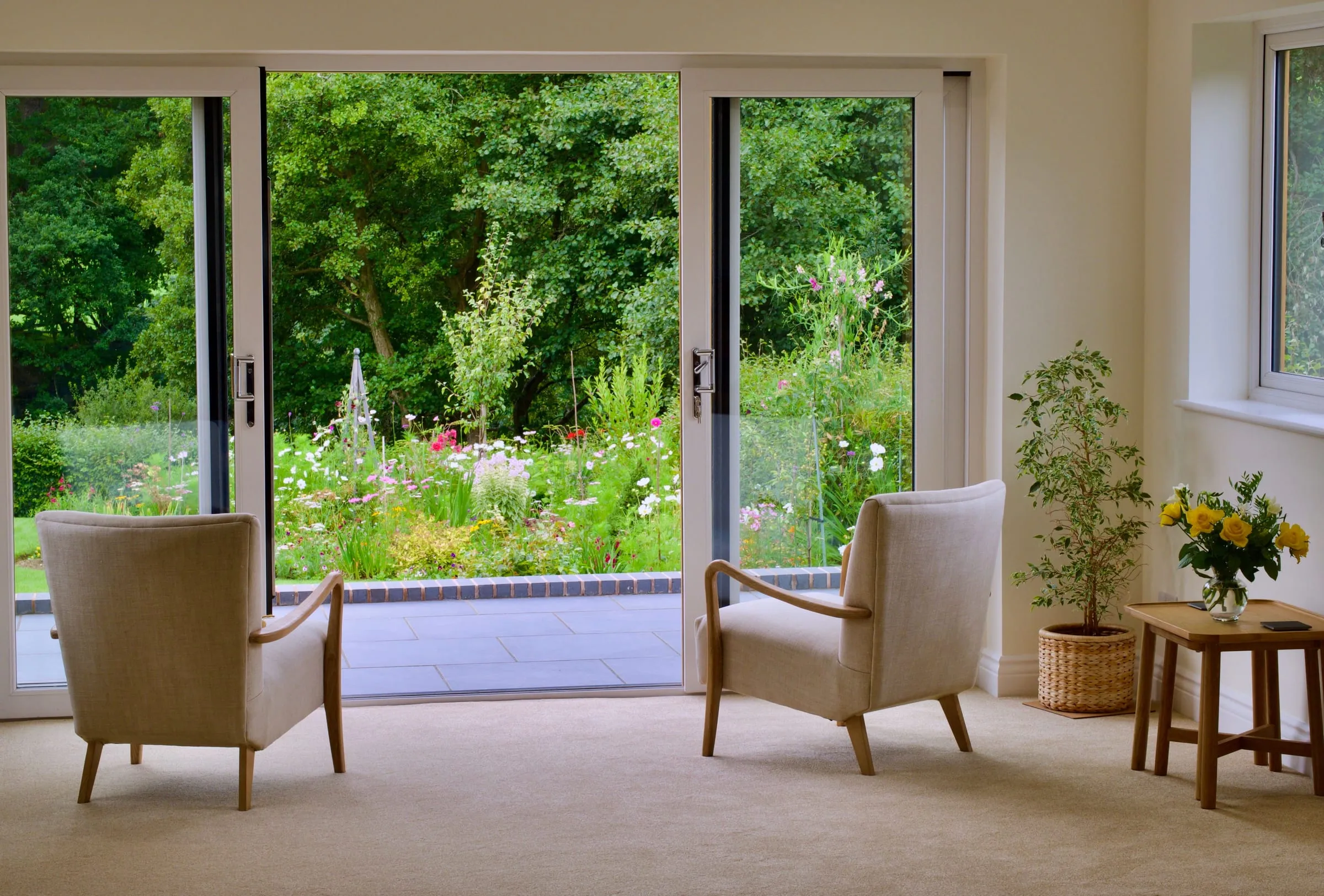 A calm, light-filled room with two armchairs and a view of a garden